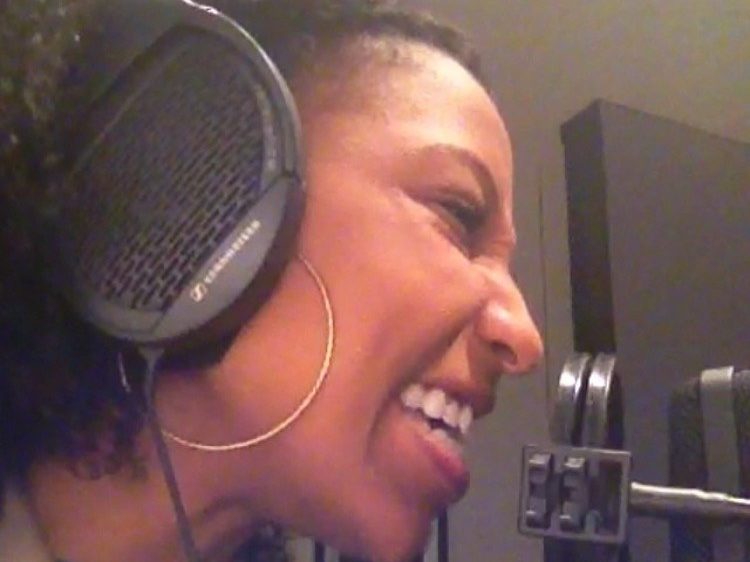 Chelsea laughing in studio headphones at the mic